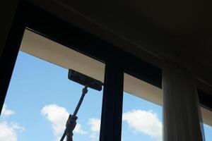 Rubber squeegee cleans a soaped window. photo