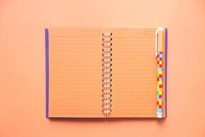 high angle view of notebook with pen on orange background photo