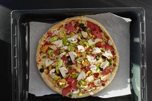 A loaded pizza on a pan with various toppings, a delicious fast food dish photo