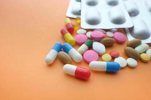 colorful pills and blister pack on orange background photo