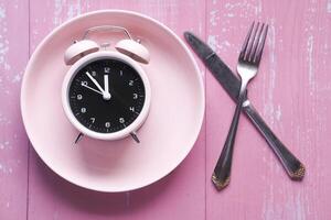 Alarm clock on plate on wooden table, top view. photo