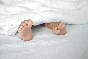 Bare feet of a child on white bed photo