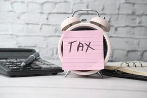 the concept tax payment. the sticky note with tax word on clock photo