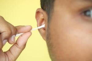 Closeup of young man using ear cotton bar photo