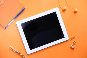 top view of digital tablet with blank screen on orange background photo