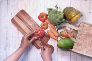 Top view of man cutting tomato on chopping board. photo