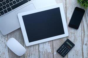 Top view of digital tablet, laptop and notepad on table photo