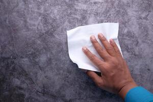 man hand with wet antibacterial wipe cleaning table photo