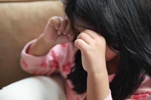 a upset child girl cover her face with hand photo