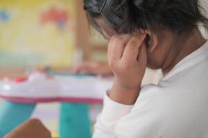 child having ear pain touching his painful ear , photo