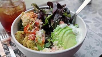 Vegetarian Buddha bowl and ice tea. Healthy and balanced diet eating. Hawaiian poke bowl with falafel, rice, avocado, tofu, vegetables. Dinner in a cafe where poke bowls are served. Fast and healthy video