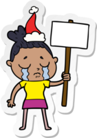 hand drawn sticker cartoon of a crying woman with protest sign wearing santa hat png