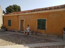 photo of a woman sitting outside an ancient house in Sardinia last summer.