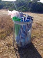 Unusable beach umbrellas thrown into a garbage can photo