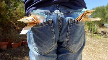 50 and 20 euro banknotes sticking out of the pockets of a blue jeans photo