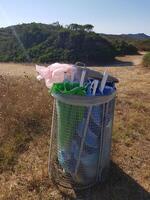 Unusable beach umbrellas thrown into a garbage can photo