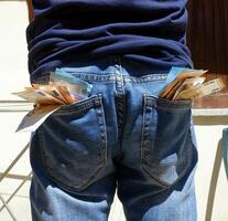 50 and 20 euro banknotes sticking out of the pockets of a blue jeans photo