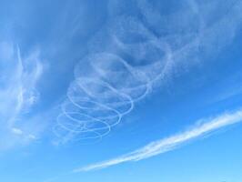 Blue sky with chemtrails from air plane, contrails, nature background, spiral shaped clouds photo