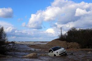 el coche estaba llevado lejos por un fuerte lluvia fluir de agua. foto