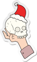 hand drawn sticker cartoon of a hand holding skull wearing santa hat png