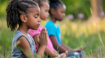 Three young girls seated in a meditative posture on green grass in a park. photo