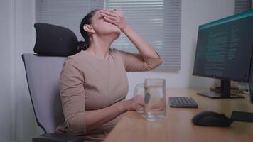 Freelancer woman at work desk on laptop and she is stressed taking pills to reduce stress video