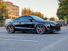 negro moderno deporte coche estacionado a ciudad estacionamiento, vehículo y transporte fondo, automotor fondo de pantalla foto