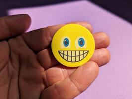 Closeup of hand holding yellow smiley face, emotions concept, happiness background, template photo