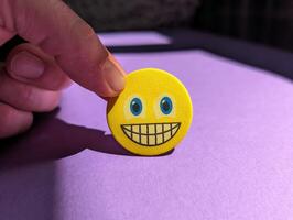 Closeup of hand holding yellow smiley face, emotions concept, happiness background, template photo