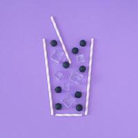Creative summer composition made with blueberries, ice cubes and drinking straw on purple background. Minimal summer drink concept. Summertime party idea. Cold refreshing cocktail layout. Flat lay. photo