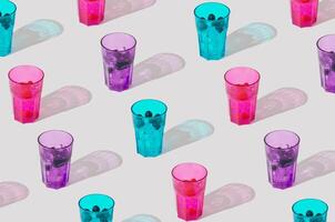 Summer sunlight pattern of colorful glasses with raspberry, blueberry and blackberry tropical refreshing drinks on white background. Minimal cocktail concept. Trendy party idea. Summer aesthetic. photo