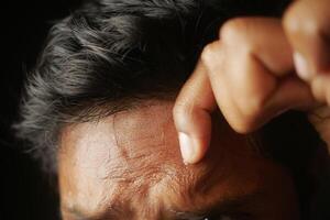 closeup of sweat on forehead against dark background , photo