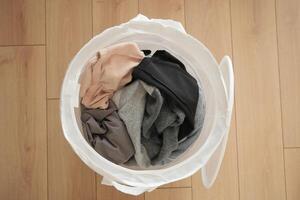 Old clothes thrown into the trash can. Disposal and recycling of clothes. photo