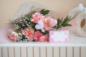 Pink rose bouquet with hearts and babys breath on table with card photo