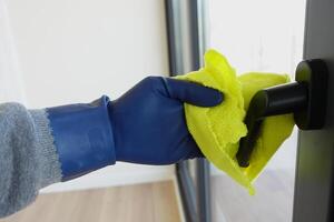 close up of person hand in gloves cleaning window glass photo