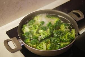 cooking broccoli in pan on electric stove photo