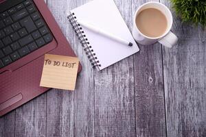 café taza, ordenador portátil y cuaderno con a hacer lista foto