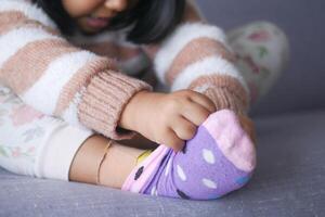 un pequeño niña molesto a tomar apagado su calcetines foto