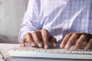 joven hombre mecanografía en teclado en oficina foto