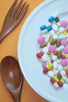 Top view of colorful medicine pills and capsules in plate. photo