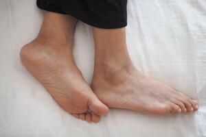 young Woman lying with bare feet in bed, photo