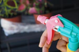 Gardener with gloves spraying a blooming fruit tree against plant diseases and pests. photo