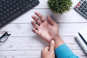 Businessman pain in hands while woking with laptop. photo