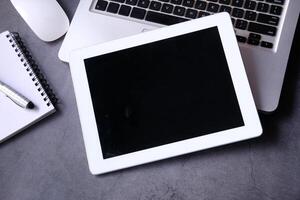 Top view of digital tablet, laptop and notepad on table photo