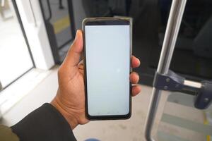 young man hand using smart phone with green screen inside of metro train photo