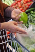 Adding a green pepper to the cart, a natural ingredient for flavorful recipes photo