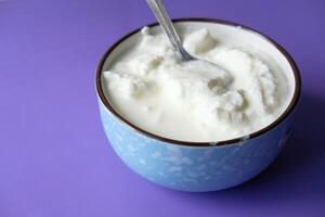 close up of fresh yogurt in a bowl on color background photo