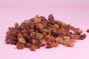 brown raisin on pink background, close up, photo