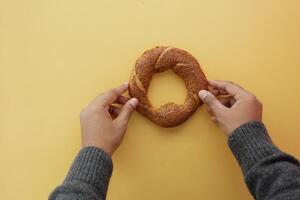 top view of hand holding Turkish Bagel Simit on table photo