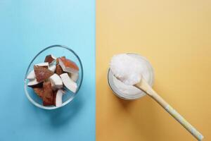 slice of fresh coconut and bottle of oil on a table photo